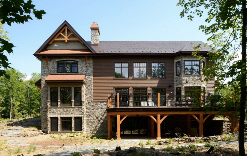 Foto della facciata di una casa grande marrone american style a tre piani con rivestimenti misti e tetto a capanna