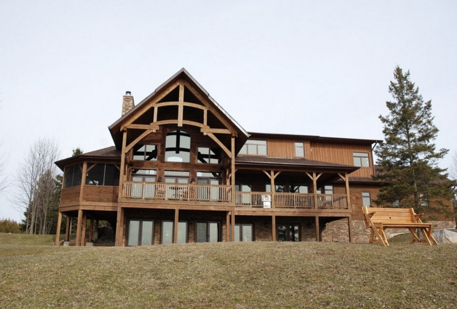 Diseño de fachada marrón rural grande de tres plantas con revestimiento de madera y tejado a dos aguas