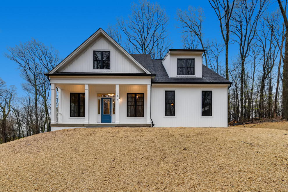 Ejemplo de fachada de casa blanca de estilo de casa de campo de tamaño medio de dos plantas con revestimiento de vinilo y tejado de teja de madera