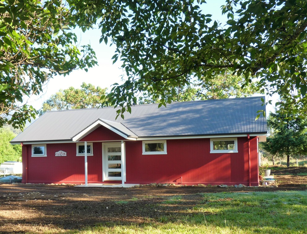 Cette photo montre une façade de maison rouge tendance en panneau de béton fibré de taille moyenne et de plain-pied avec un toit en métal.