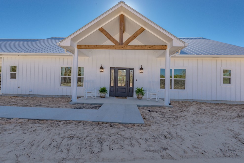 Mid-sized farmhouse white one-story wood house exterior photo in Austin with a hip roof and a metal roof