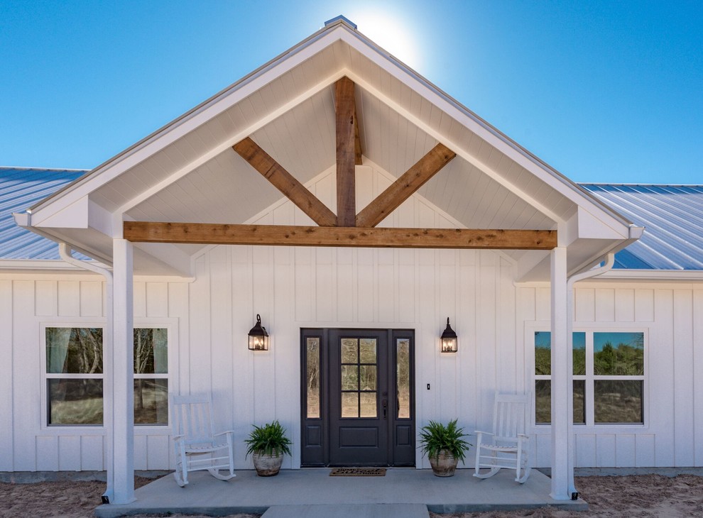 Foto della villa bianca country a un piano di medie dimensioni con rivestimento in legno, tetto a padiglione e copertura in metallo o lamiera