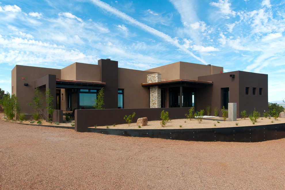 Inspiration pour une façade de maison marron sud-ouest américain en stuc de taille moyenne et de plain-pied avec un toit plat.