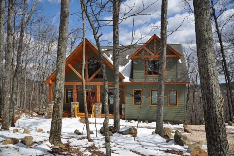 На фото: двухэтажный, деревянный, зеленый частный загородный дом среднего размера в стиле рустика с двускатной крышей и крышей из гибкой черепицы