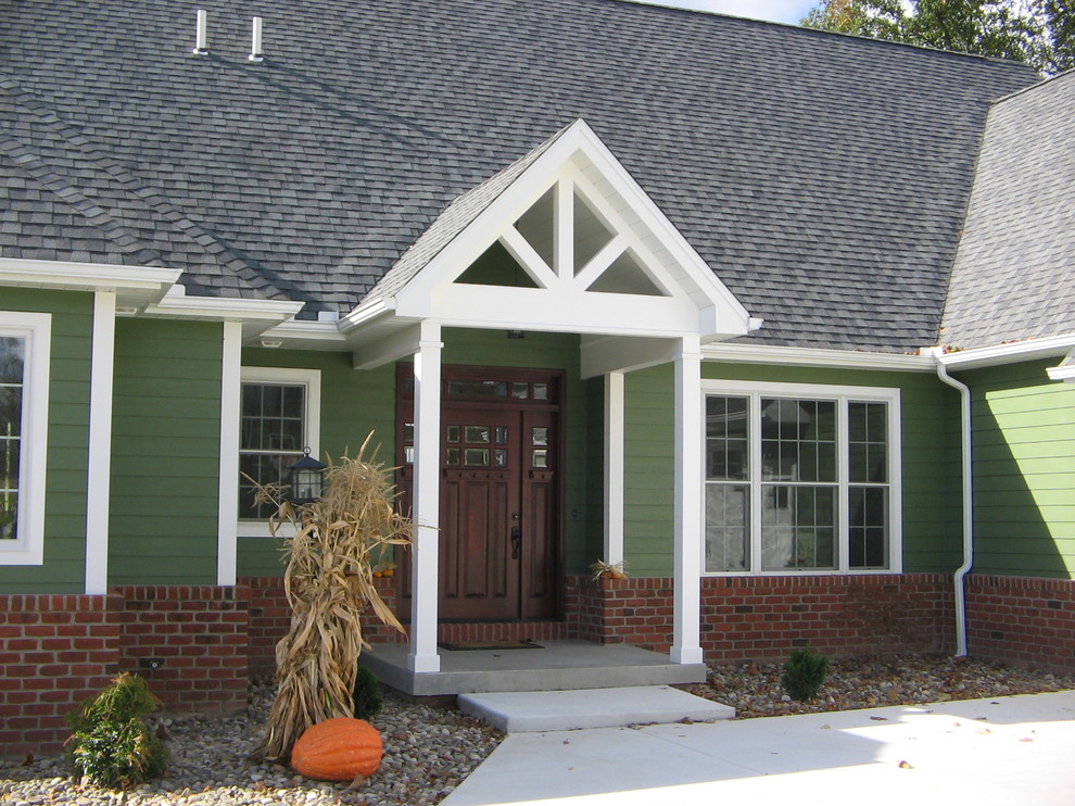 Modelo de fachada de casa verde clásica grande de dos plantas con revestimientos combinados, tejado a dos aguas y tejado de teja de madera