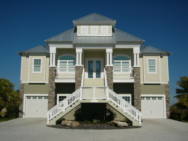 This is an example of a large and beige coastal house exterior in Tampa with three floors, concrete fibreboard cladding and a pitched roof.