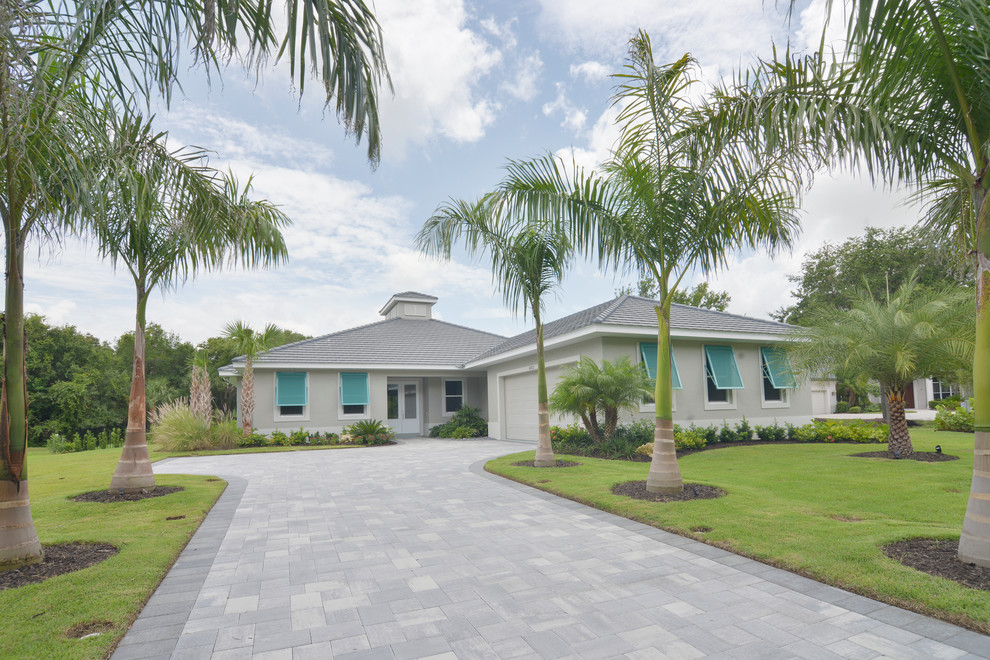 Mid-sized beach style gray one-story stucco exterior home photo in Tampa with a hip roof