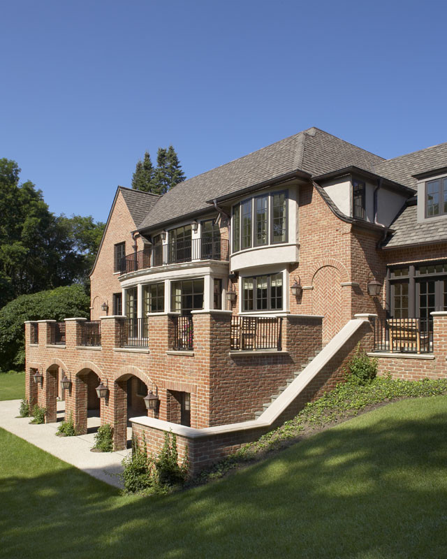 Foto della villa ampia marrone classica a tre piani con rivestimento in mattoni, tetto a padiglione e copertura a scandole