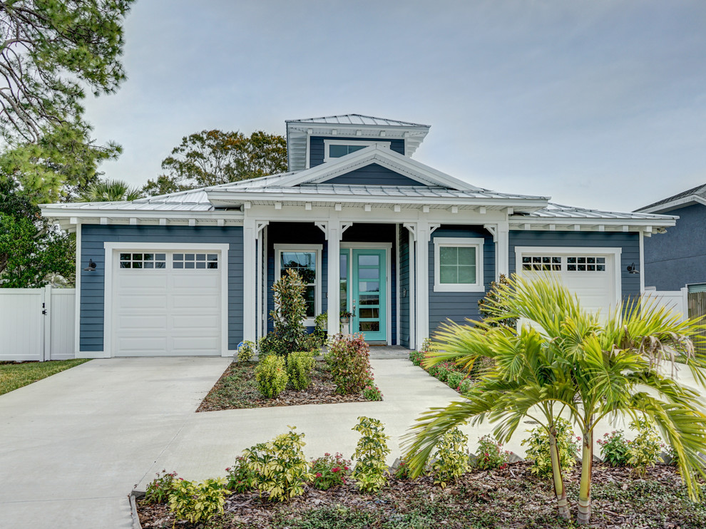 Cette photo montre une façade de maison bleue bord de mer en panneau de béton fibré de taille moyenne et de plain-pied avec un toit à deux pans et un toit en métal.