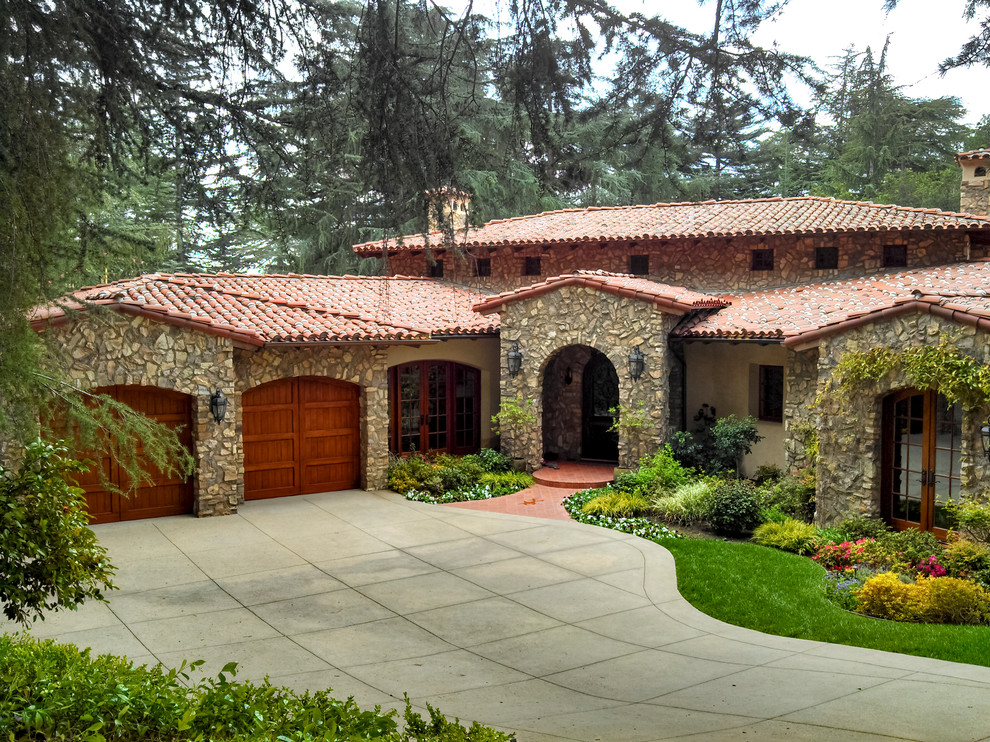 Пример оригинального дизайна: разноцветный частный загородный дом в средиземноморском стиле с облицовкой из камня, вальмовой крышей и черепичной крышей