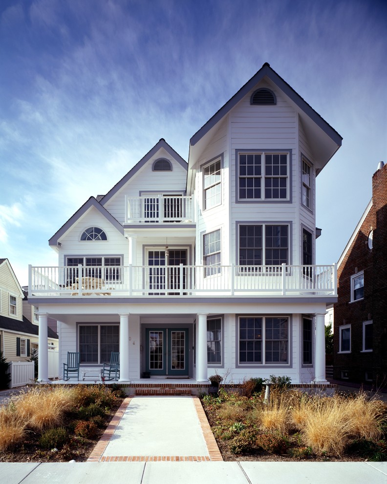 Cette photo montre une grande façade de maison blanche bord de mer en panneau de béton fibré à deux étages et plus avec un toit à deux pans et un toit en shingle.