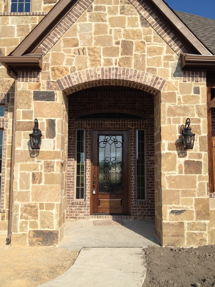 Photo of a large and brown traditional bungalow house exterior in Dallas with stone cladding and a hip roof.
