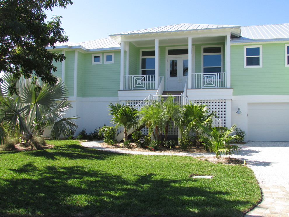Large beach style green two-story concrete fiberboard house exterior photo in Miami with a hip roof and a metal roof