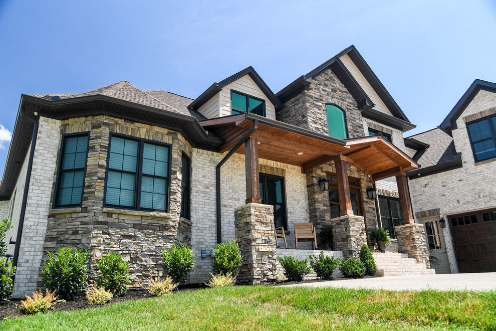 Design ideas for a gey farmhouse two floor house exterior in Nashville with stone cladding.