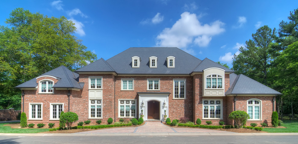 Inspiration for a large timeless two-story brick exterior home remodel in Charlotte with a hip roof