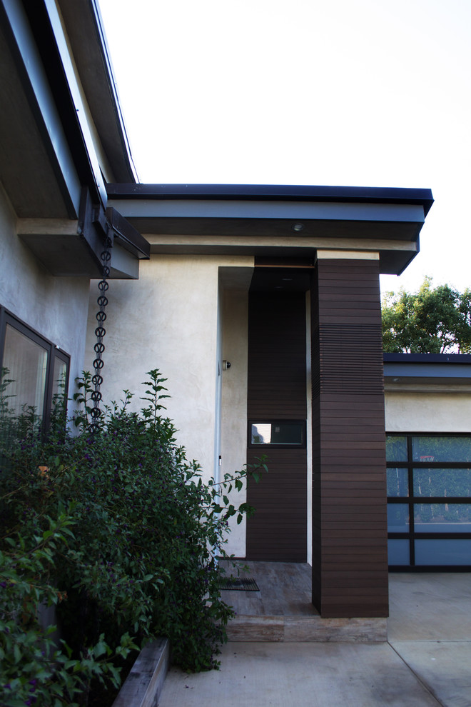 Idée de décoration pour une façade de maison beige minimaliste en stuc de taille moyenne et à un étage.