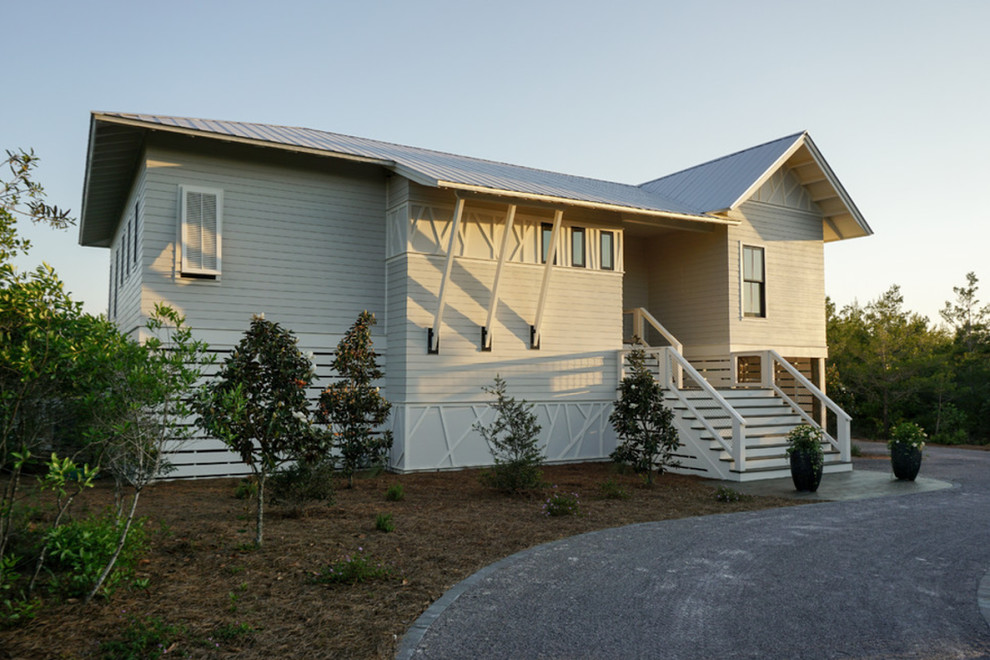 Diseño de fachada de casa beige costera de tamaño medio de una planta con revestimiento de madera, tejado a dos aguas y tejado de teja de madera