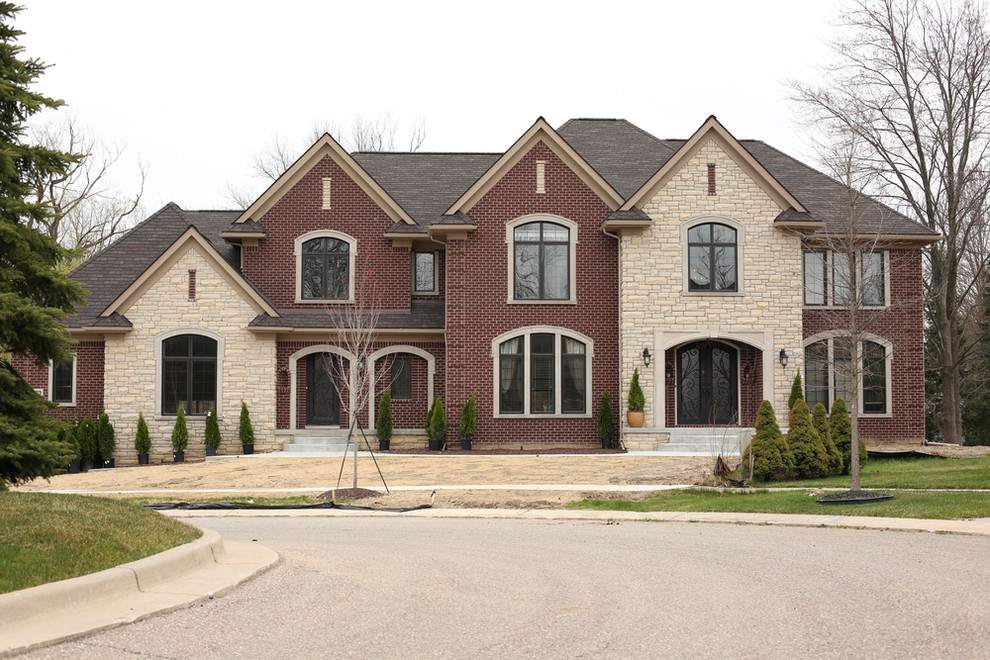 Mid-sized traditional red two-story brick house exterior idea in Detroit with a hip roof and a shingle roof