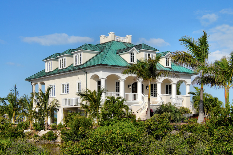 Diseño de fachada de casa beige costera grande de dos plantas con revestimiento de estuco, tejado a cuatro aguas y tejado de metal