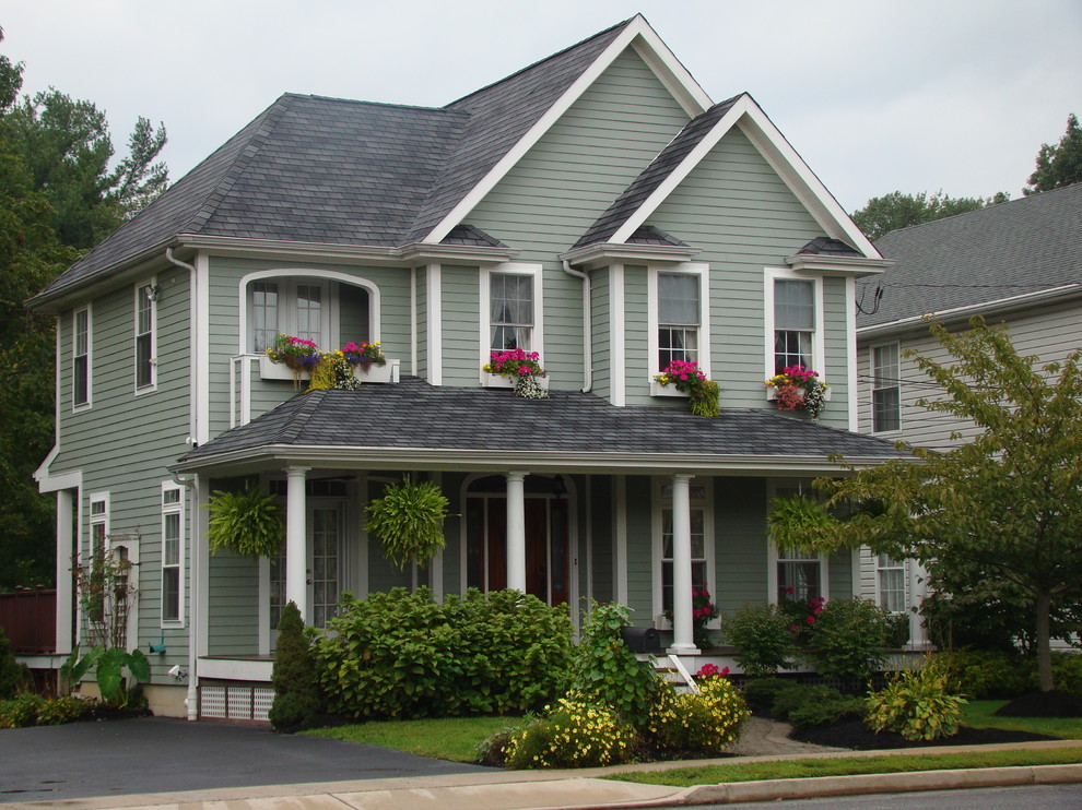 Aménagement d'une façade de maison verte classique en panneau de béton fibré de taille moyenne et à un étage avec un toit à quatre pans et un toit en shingle.