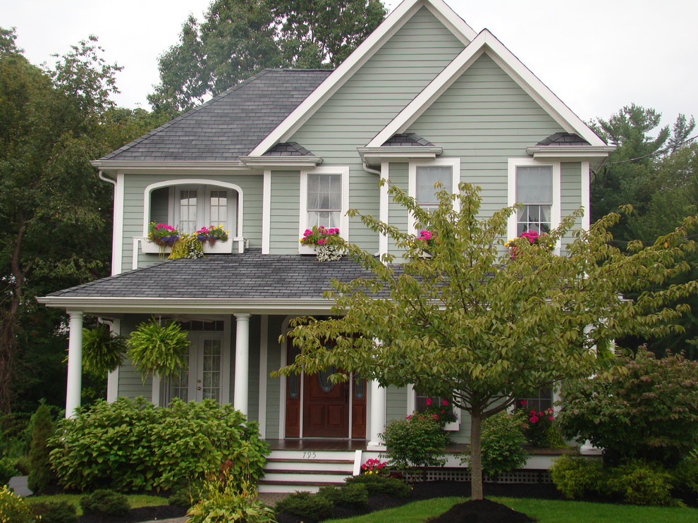 Imagen de fachada de casa verde tradicional de tamaño medio de dos plantas con revestimiento de aglomerado de cemento, tejado a cuatro aguas y tejado de teja de madera