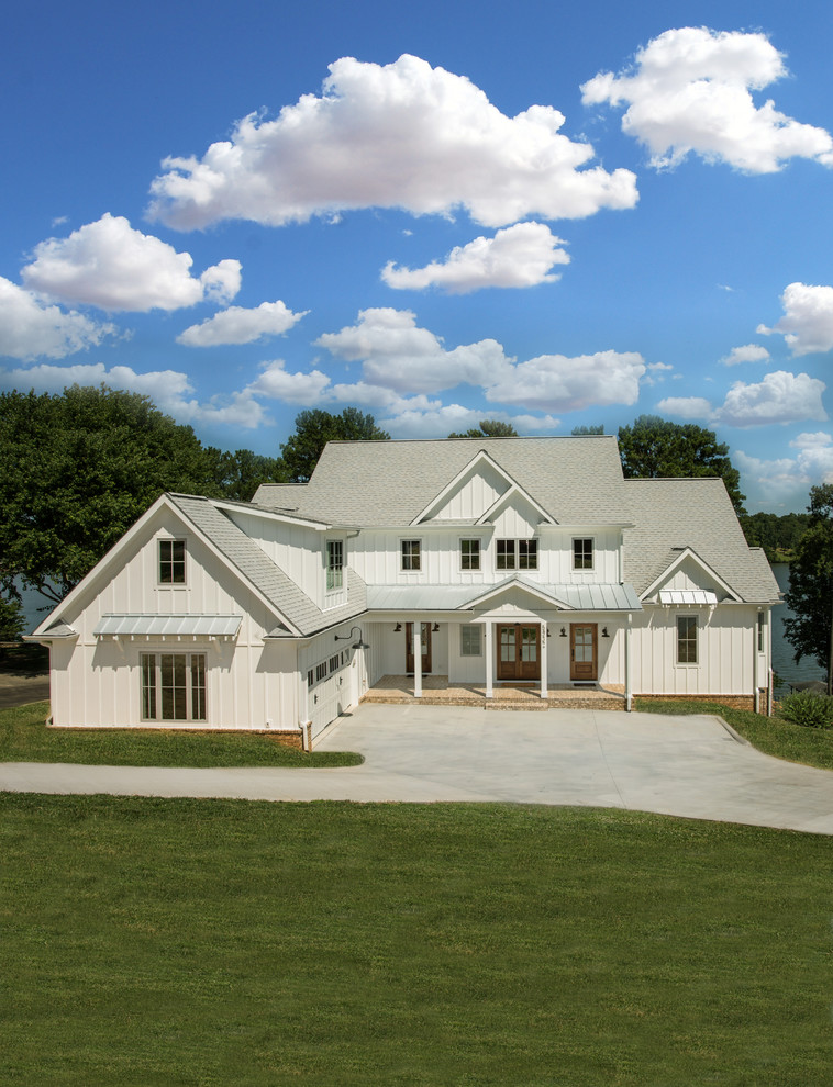 На фото: двухэтажный, белый частный загородный дом в стиле кантри с двускатной крышей и крышей из гибкой черепицы с