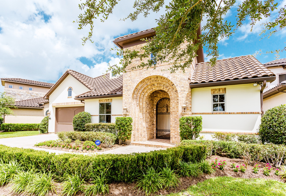 Large and beige mediterranean two floor detached house in Houston with mixed cladding, a hip roof and a tiled roof.