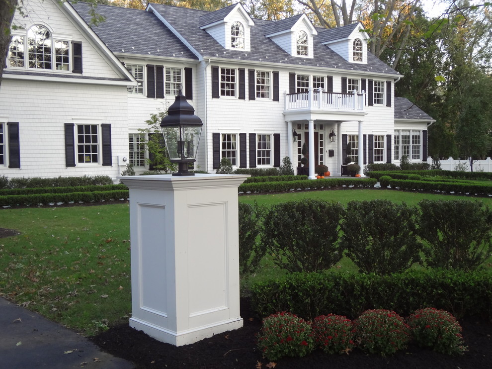 Imagen de fachada blanca clásica grande de dos plantas con revestimiento de madera y tejado a dos aguas