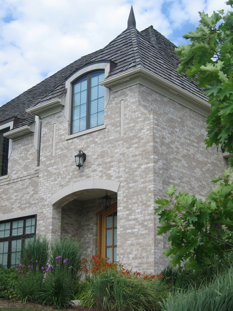 На фото: большой, двухэтажный, серый частный загородный дом в классическом стиле с облицовкой из камня, вальмовой крышей и крышей из гибкой черепицы