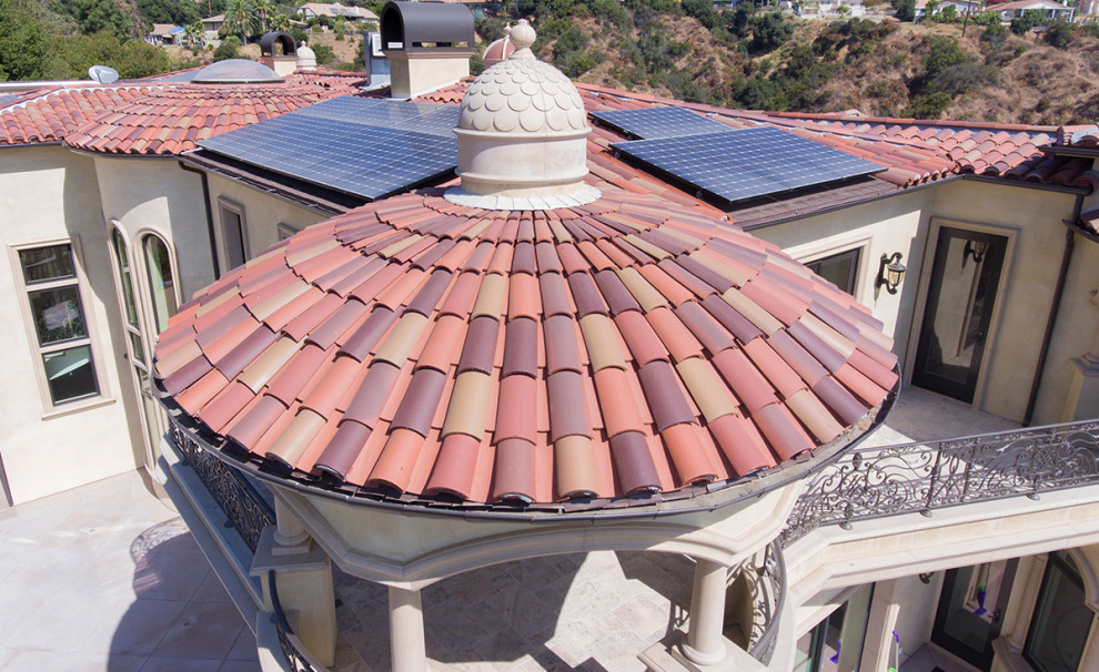 Foto della villa beige mediterranea a tre piani con rivestimento in stucco, tetto a padiglione e copertura in tegole