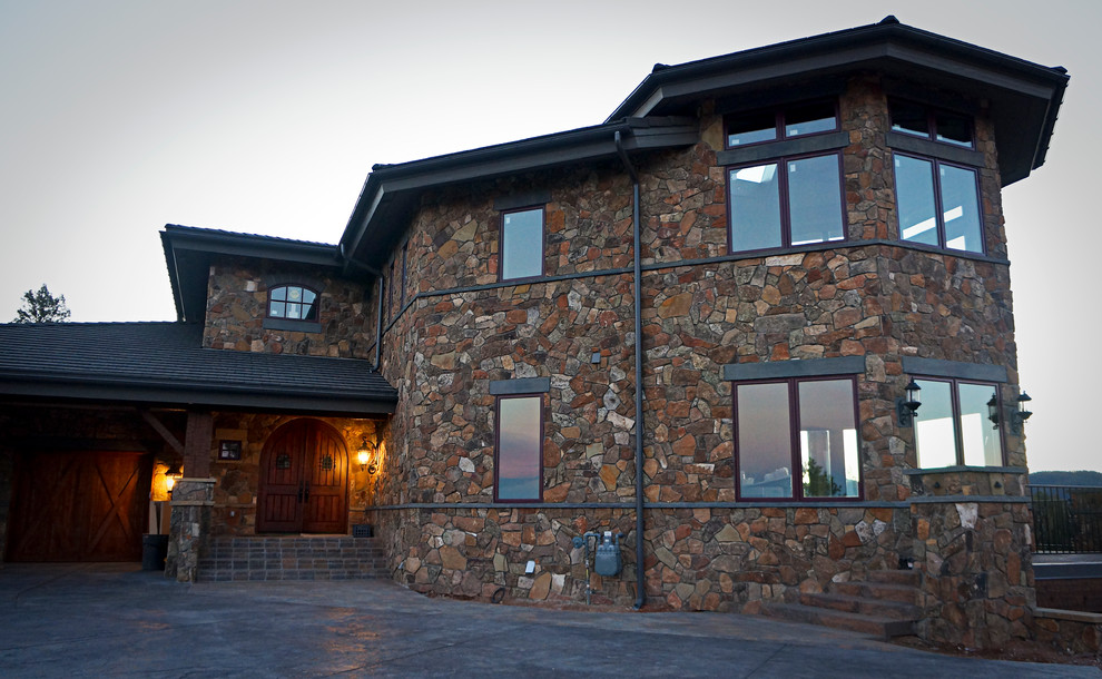 На фото: огромный, трехэтажный, коричневый дом в стиле рустика с облицовкой из камня с