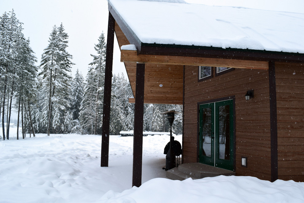 Cette photo montre une façade de maison marron montagne en bois de taille moyenne et à un étage avec un toit en métal.