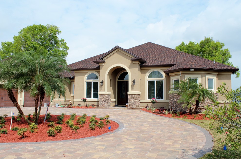 This is an example of a medium sized and beige mediterranean bungalow render house exterior in Jacksonville with a hip roof.