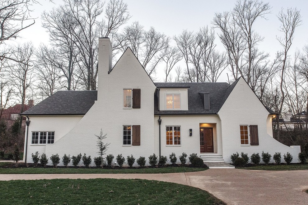 Пример оригинального дизайна: двухэтажный, белый дом среднего размера в стиле неоклассика (современная классика) с облицовкой из цементной штукатурки и двускатной крышей
