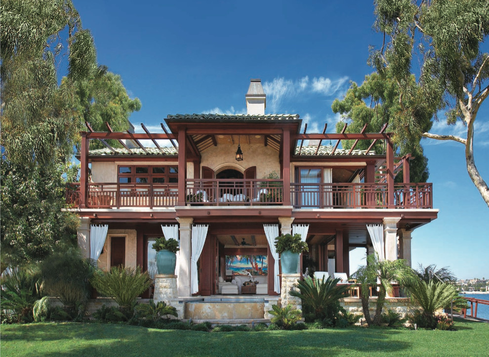 Esempio della facciata di una casa grande beige tropicale a due piani con rivestimento in stucco e tetto a padiglione