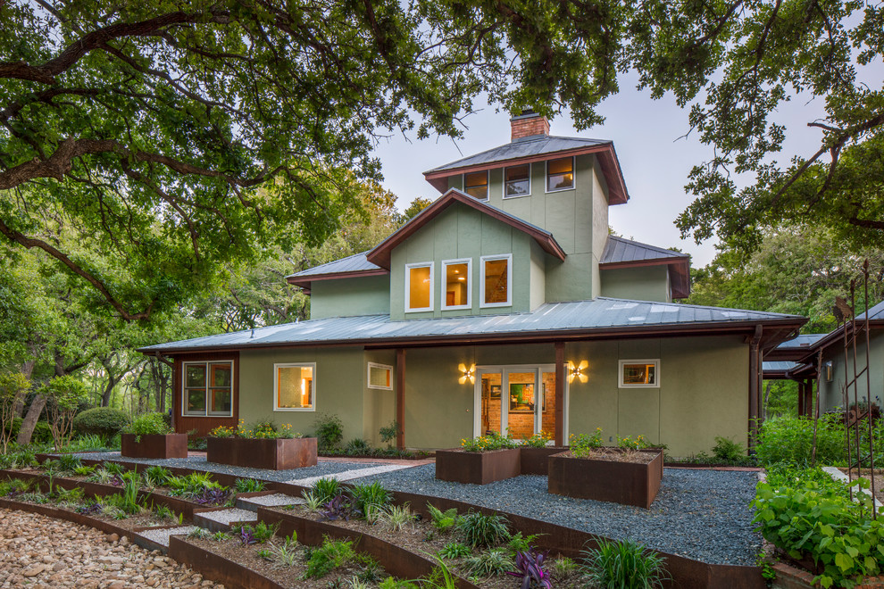 Zweistöckiges Landhausstil Einfamilienhaus mit Blechdach, Putzfassade und grüner Fassadenfarbe in Austin