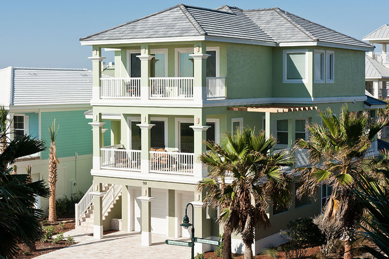 Cette image montre une grande façade de maison verte marine en stuc à deux étages et plus.