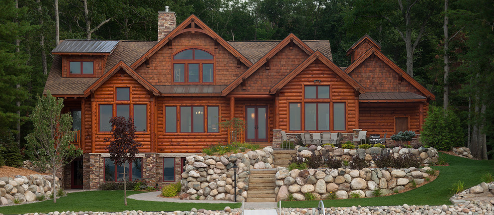 На фото: большой, трехэтажный, деревянный, коричневый дом в стиле рустика с двускатной крышей для охотников с