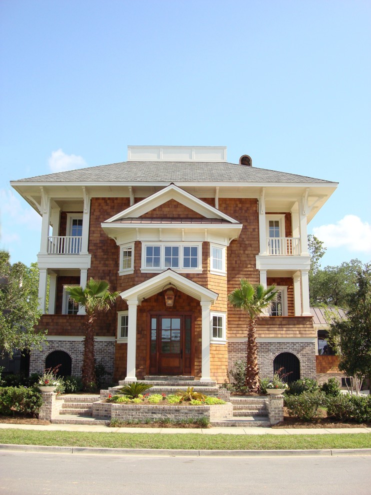 Immagine della villa grande marrone tropicale a tre piani con rivestimento in legno, tetto a padiglione e copertura a scandole