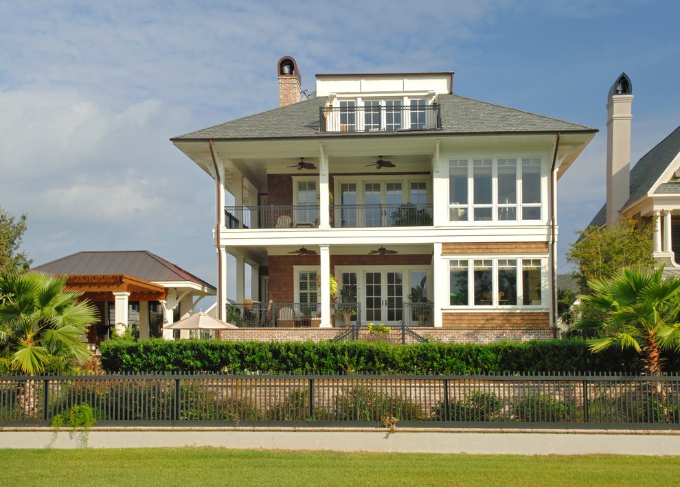 Ejemplo de fachada de casa marrón y gris costera grande de tres plantas con tejado a cuatro aguas, revestimiento de madera, tejado de varios materiales y teja