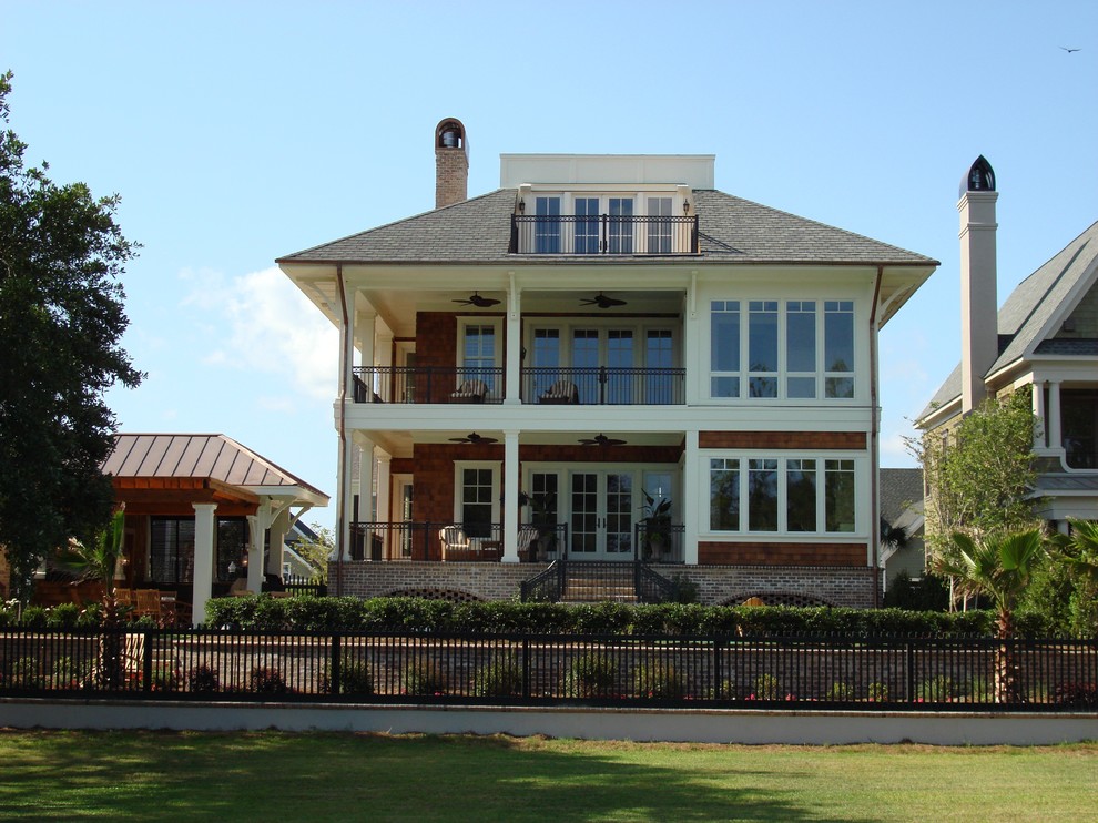 Esempio della villa grande marrone stile marinaro a tre piani con rivestimento in legno, tetto a padiglione, copertura mista e tetto nero