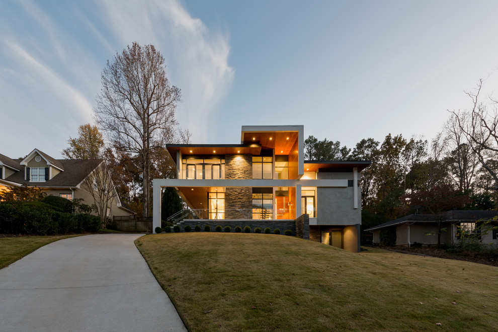 Imagen de fachada de casa gris contemporánea de tres plantas con tejado plano y revestimientos combinados