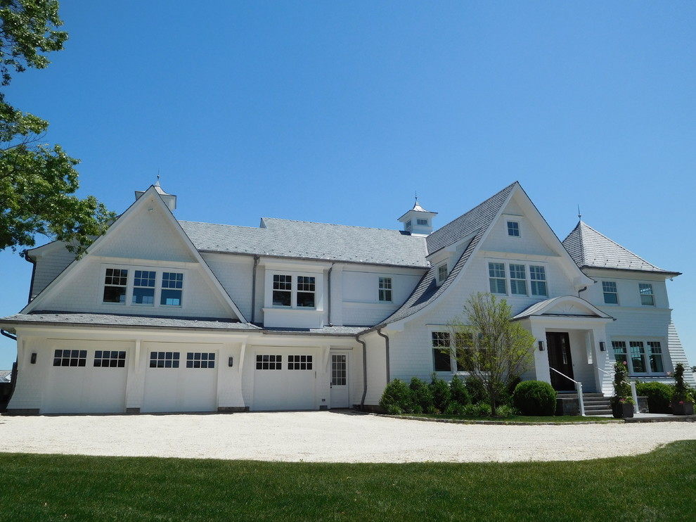 This is an example of a large and white coastal two floor detached house in New York with wood cladding, a hip roof and a shingle roof.