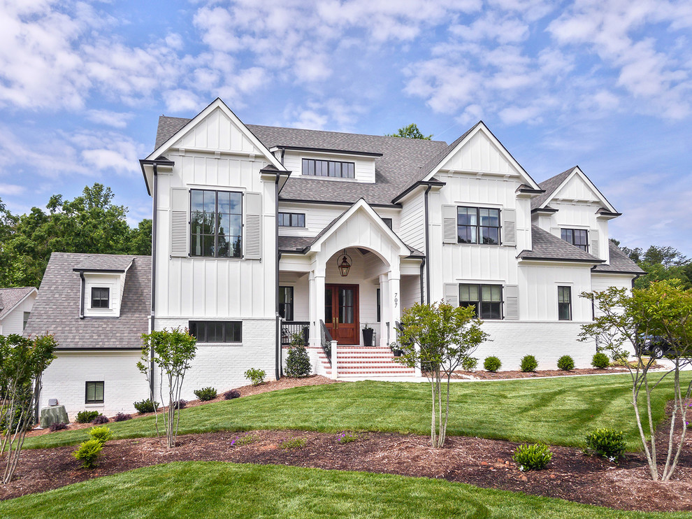 Example of a large farmhouse white three-story brick exterior home design in Charlotte with a mixed material roof