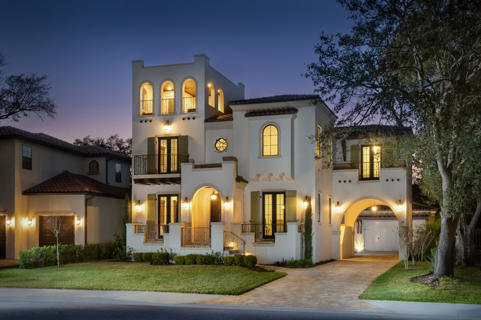 This is an example of a beige mediterranean detached house in Tampa with three floors, a hip roof and a tiled roof.