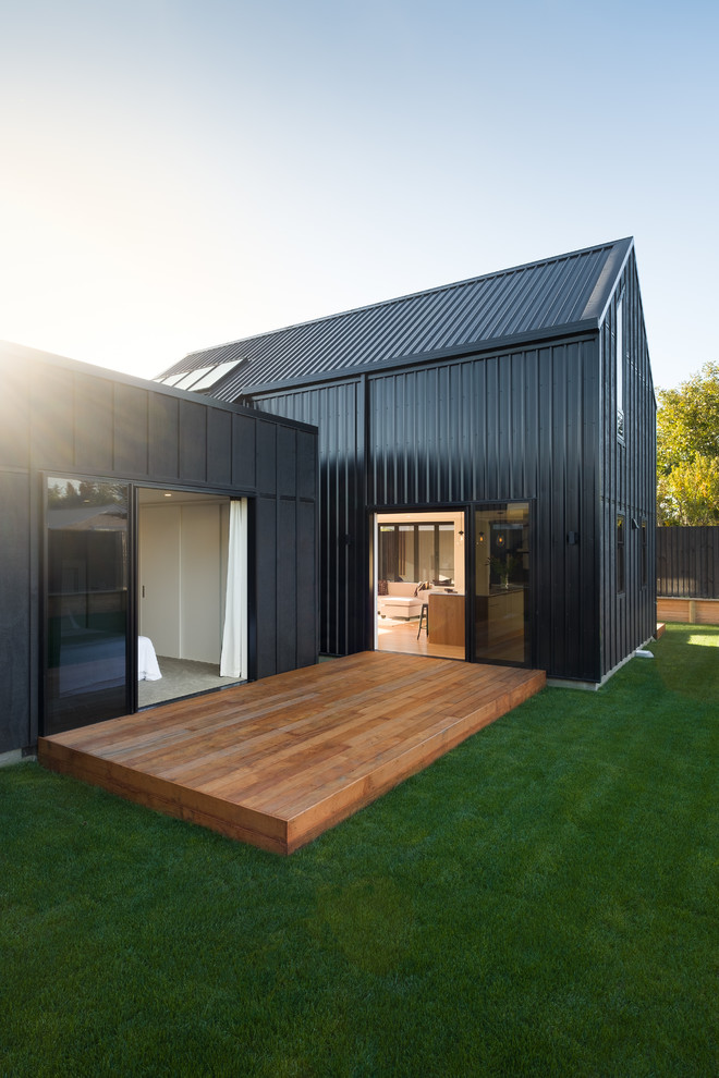 Ispirazione per la facciata di una casa a schiera piccola nera stile marinaro a due piani con rivestimento in legno, tetto a capanna e copertura in metallo o lamiera