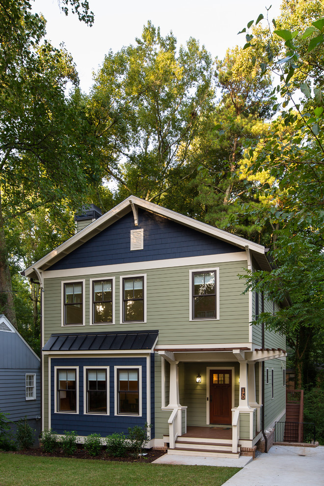 На фото: трехэтажный, зеленый дом среднего размера в стиле кантри с облицовкой из ЦСП и двускатной крышей с