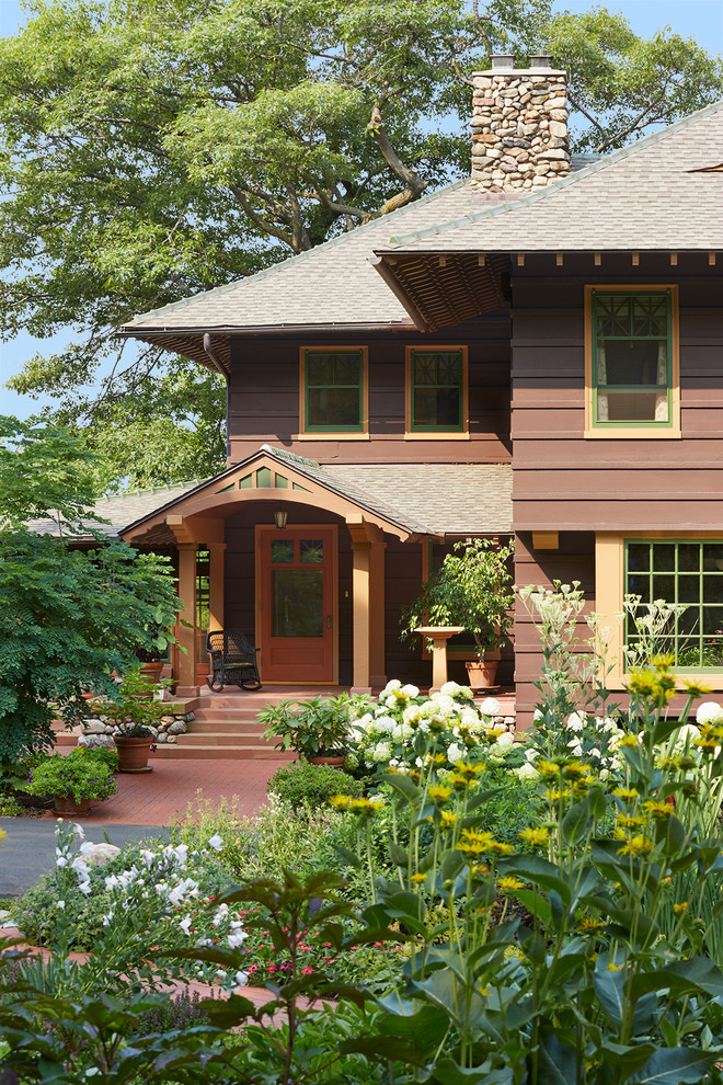 This is an example of a large and brown classic two floor house exterior in Minneapolis with wood cladding and a hip roof.