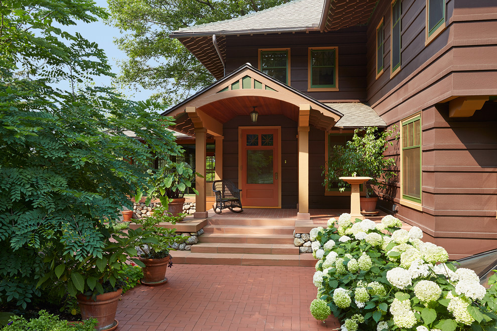 This is an example of a large and brown traditional two floor house exterior in Minneapolis with wood cladding.