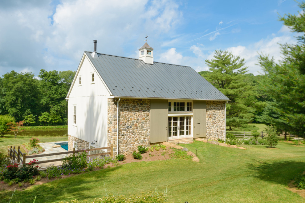 Inspiration for a rustic white two-story stone gable roof remodel in Philadelphia